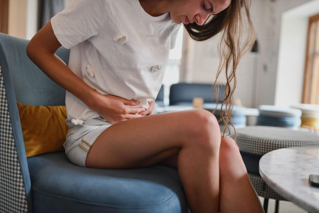 Young woman holding her lower abdomen, representing hormonal imbalance and Polycystic Ovary Syndrome (PCOS).